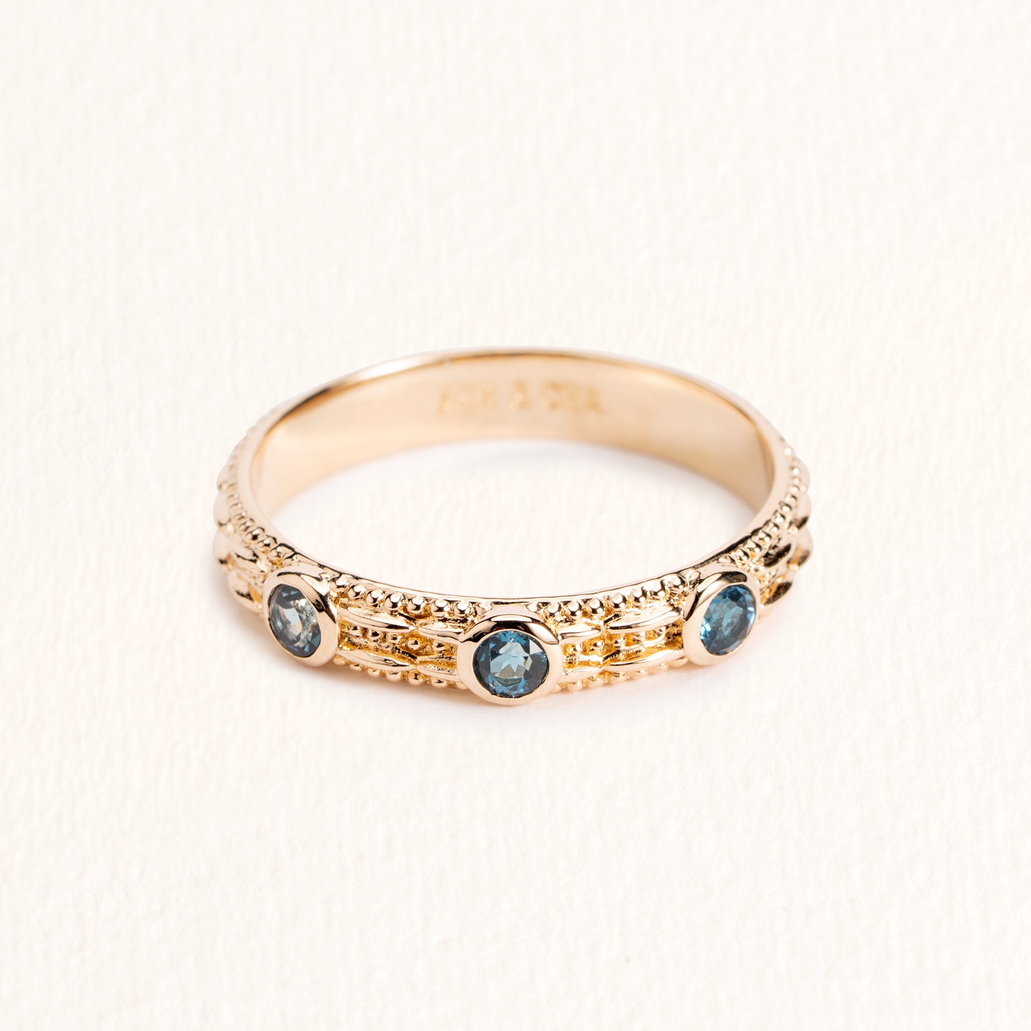 Bague Astra dorée en plaqué or 18 carats ornée de trois topazes London Blue bleu profond et d’un anneau fin texturé