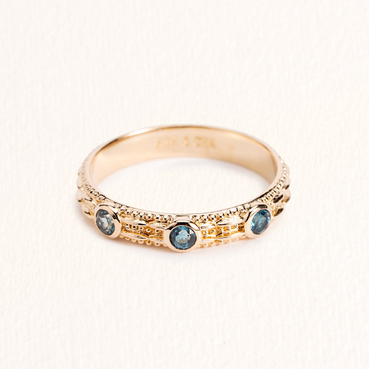 Bague Astra dorée en plaqué or 18 carats ornée de trois topazes London Blue bleu profond et d’un anneau fin texturé