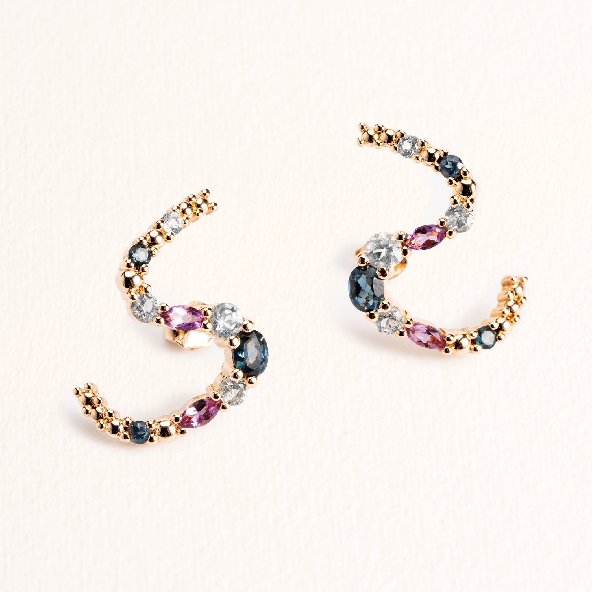 Boucles d’oreilles Elsa dorées en plaqué or 18 carats ornées de pierres naturelles bleues, violettes et blanches le long de lignes courbés en S