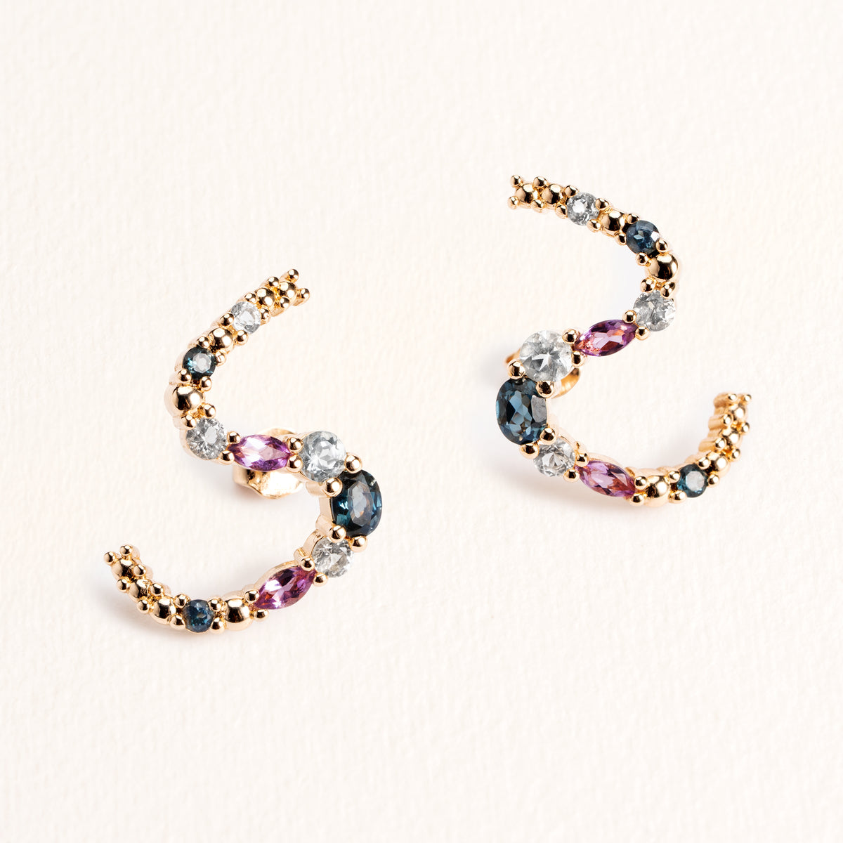 Boucles d’oreilles Elsa dorées en plaqué or 18 carats ornées de pierres naturelles bleues, violettes et blanches le long de lignes courbés en S