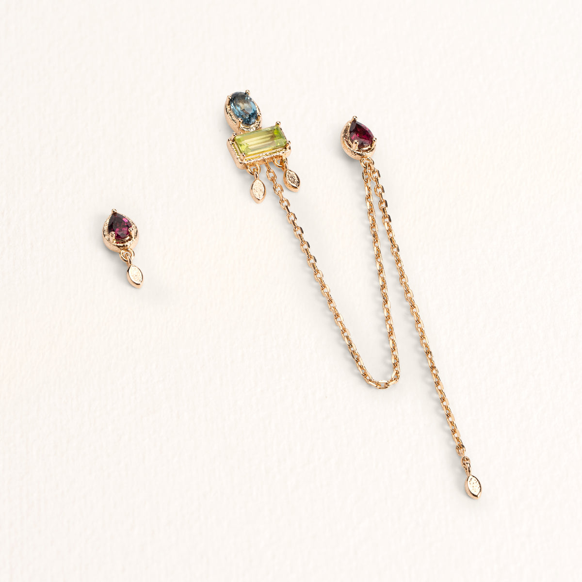 Boucles d’oreilles Sienna dorées en plaqué or 18 carats, avec une boucle longue reliant deux trous ornée de topaze London Blue, rhodolite et péridot et une puce d’oreille ornée d'une rhodolite
