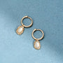 Créoles Ilona dorées en plaqué or 18 carats texturées avec pendentif en nacre blanche irisée aux contours irréguliers et arrondis