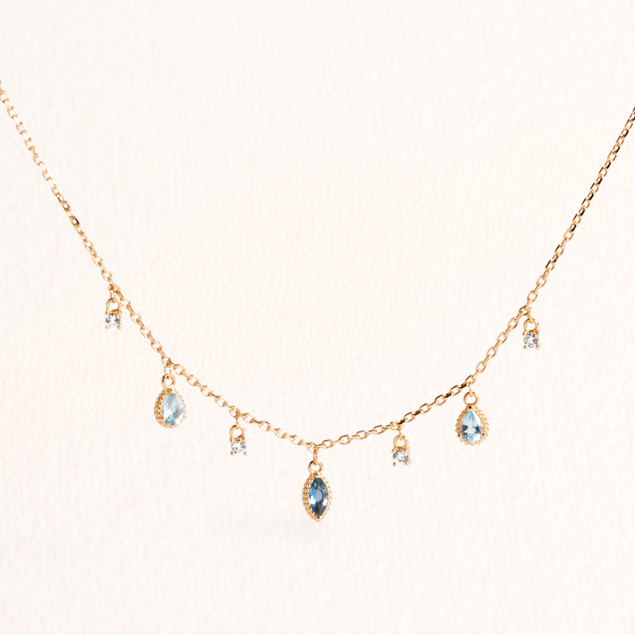 Collier Mira doré en plaqué or 18 carats avec chaîne fine ornée de topazes pendantes bleu profond, bleu clair et blanches