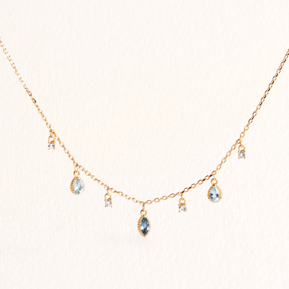 Collier Mira doré en plaqué or 18 carats avec chaîne fine ornée de topazes pendantes bleu profond, bleu clair et blanches