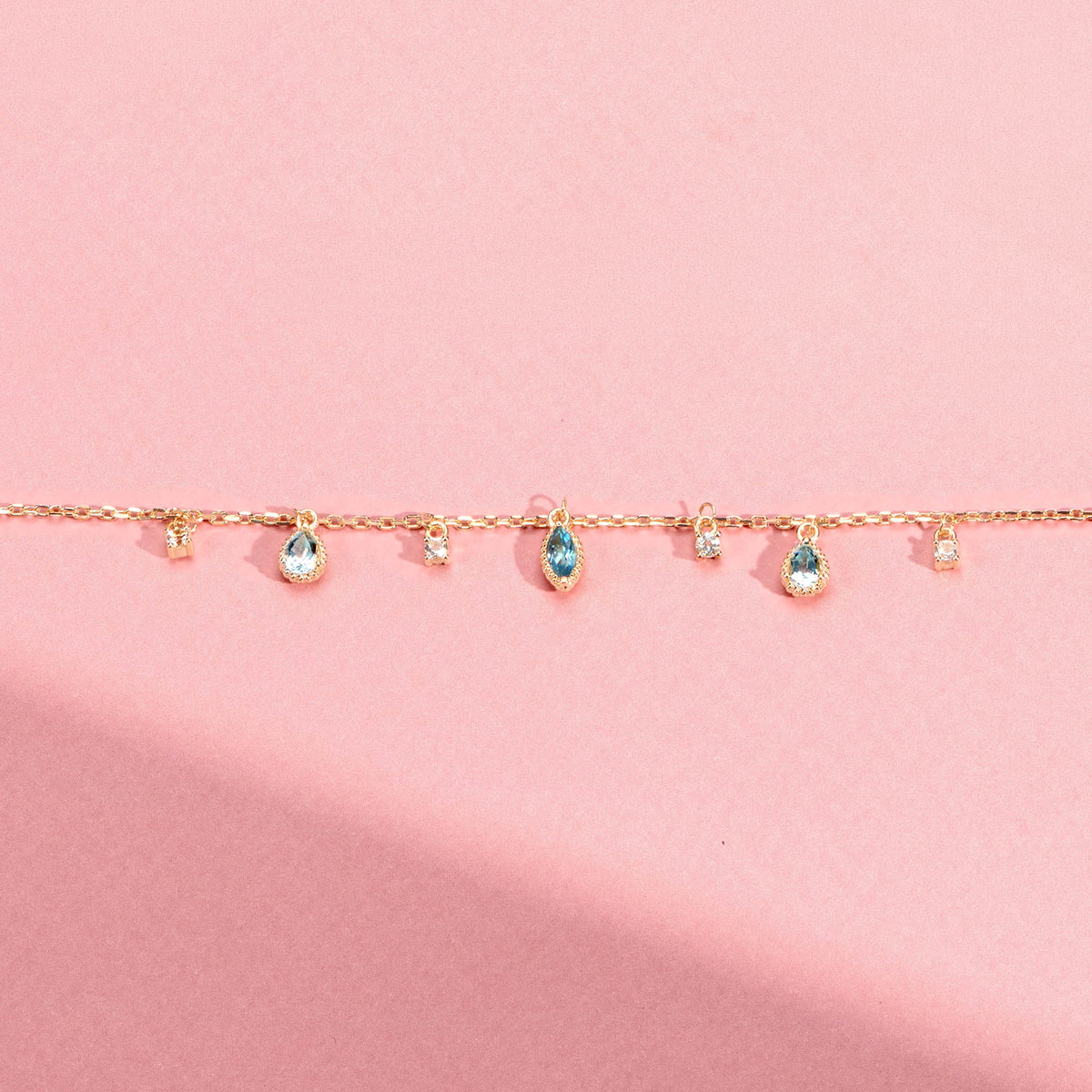 Bracelet Mira doré en plaqué or 18 carats avec chaîne fine ornée de topazes bleu profond, bleu clair et blanches