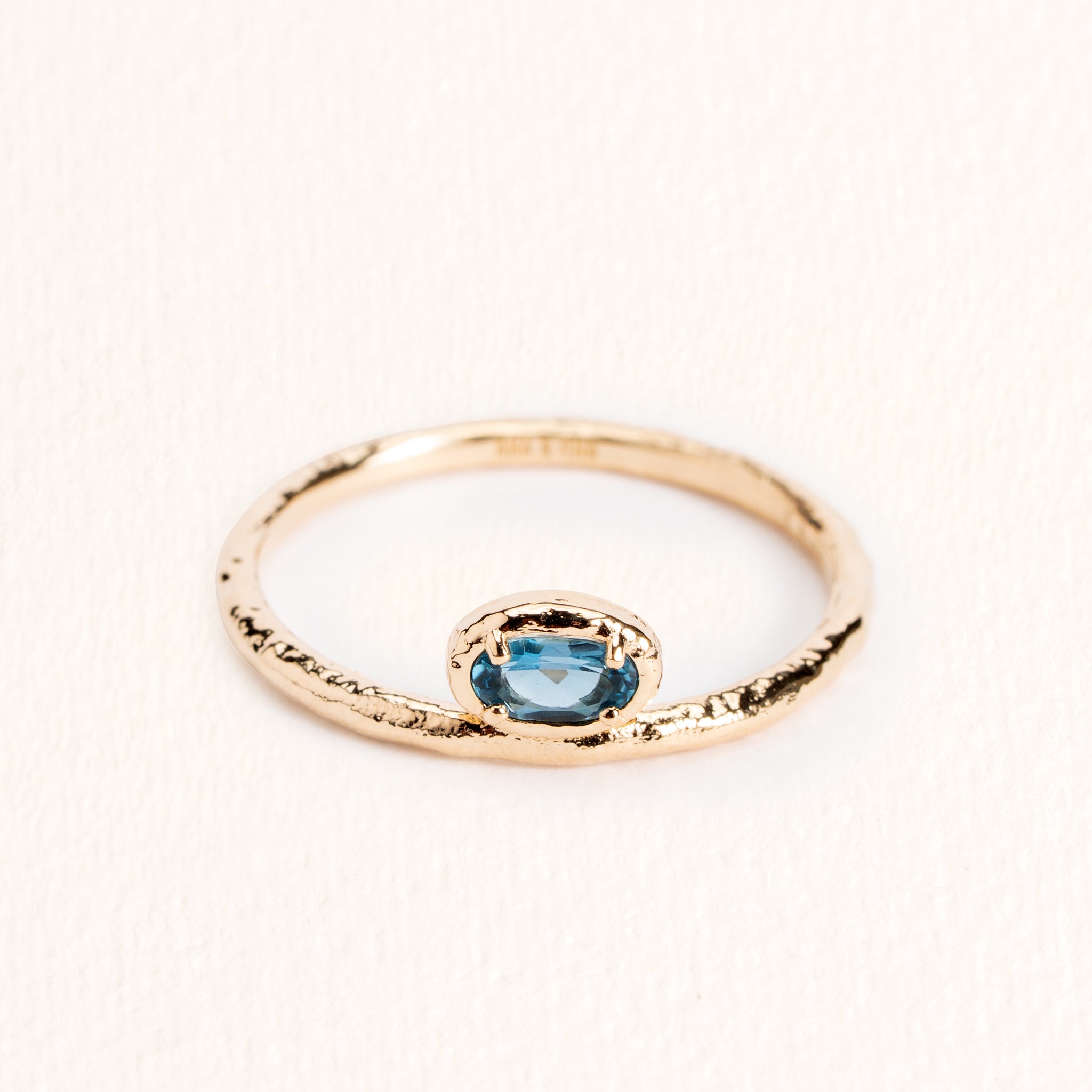 Bague Sienna dorée en plaqué or 18 carats avec anneau fin texturé, ornée d’une topaze ovale London Blue au bleu profond