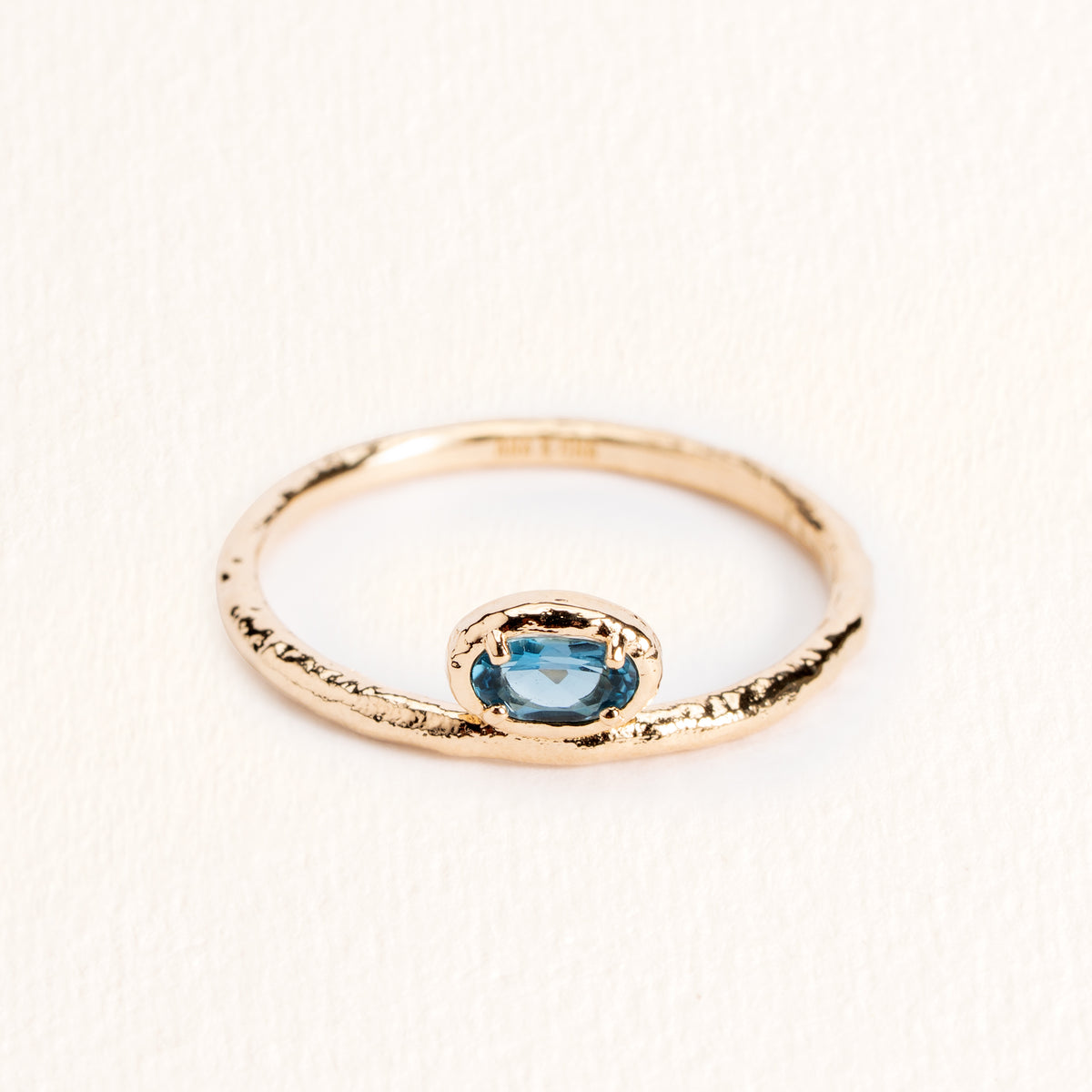 Bague Sienna dorée en plaqué or 18 carats avec anneau fin texturé, ornée d’une topaze ovale London Blue au bleu profond